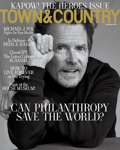 Magazine cover featuring Michael J. Fox in black and white, with a headline about philanthropy and health issues, against a neutral backdrop.