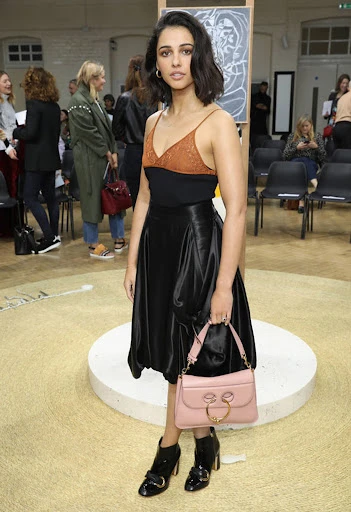 Naomi Scott attends the Chloé Womenswear Fall/Winter 2020/2021 show during Paris Fashion Week, wearing a black skirt and pink purse.