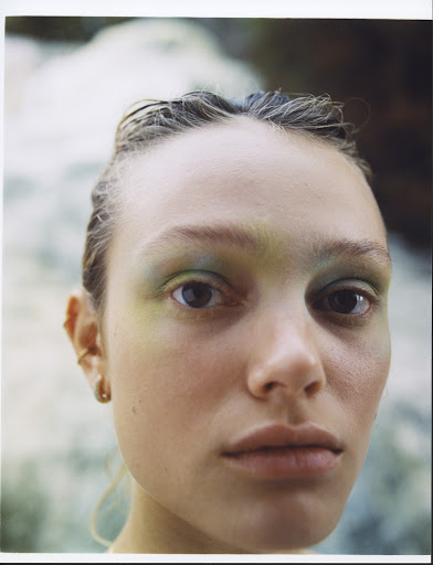 Close-up portrait of a woman with wet-look hair and pastel green eyeshadow photographed by Marco Braca