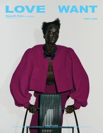 Fashion editorial shot of a Black model, Nyaueth Riam, wearing a magenta suit jacket and matching pants, posing with a metal chair.
