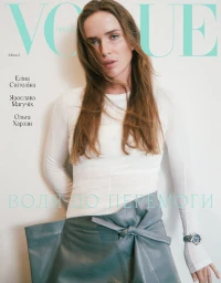 Woman in white long-sleeve top and grey leather skirt standing against a plain white background
