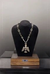 Diamond winged angel pendant necklace displayed on a black bust stand with a wooden base.