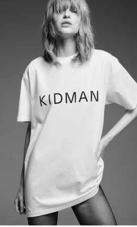 Model wearing a white t-shirt with Kidman text and dark tights against a grey background