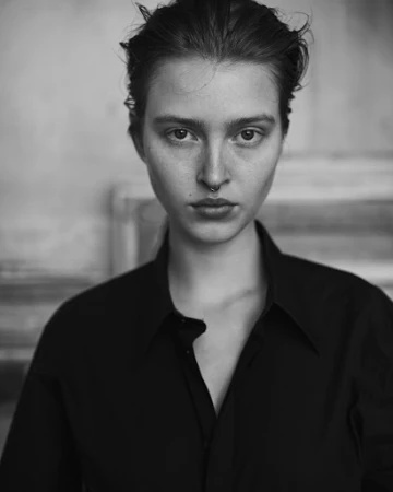 Monochrome portrait of a woman with dark hair and a septum piercing wearing a black shirt