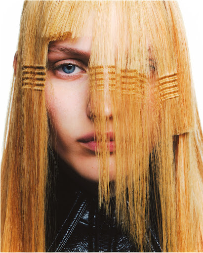 Close-up fashion portrait of a woman with blonde hair and crimped strands covering her face, wearing a black leather jacket.