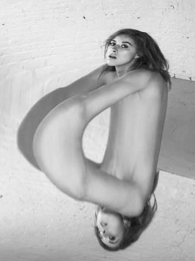 Striking black and white portrait of a woman with expressive eyes, complemented by a refracted mirrored reflection and white brick backdrop.