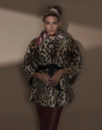 Adult woman poses in a vintage-inspired, leopard-print coat with a red pencil skirt against a neutral background with lighting effects.