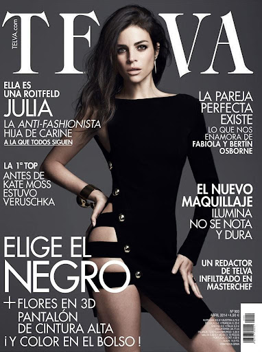 A fashion magazine cover featuring a brunette adult woman in a black dress with cutouts, posing against a dark grey gradient background.