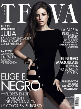 A fashion magazine cover featuring a brunette adult woman in a black dress with cutouts, posing against a dark grey gradient background.