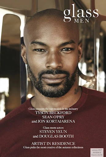 Glass Men magazine cover featuring a headshot of a bald Black male model in a maroon shirt, looking directly at the viewer. 