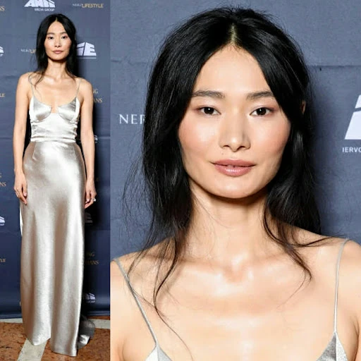 Asian woman in silver gown at event. Portrait of elegant woman with long black hair in formal attire at indoor venue backdrop.