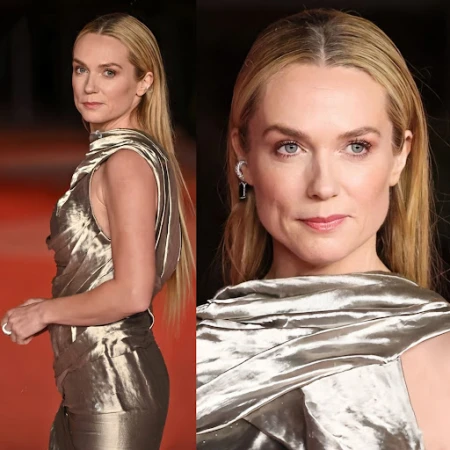 Close-up studio shot of a blonde woman in a draped, metallic bronze dress. Light skin, bright eyes, straight blonde hair, evening dress.