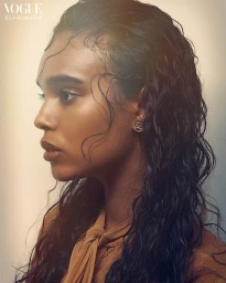 Profile portrait of a young woman with wet dark hair styling by Sheridan Ward against a light neutral background.