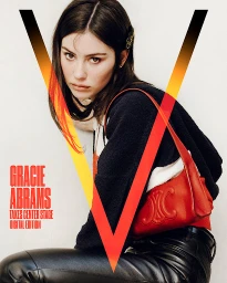 Portrait of Gracie Abrams wearing a black top and leather trousers with a red shoulder bag against a white wall