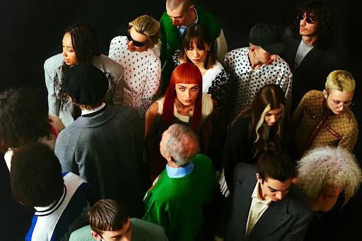 High-angle group portrait of diverse fashion models with varied hairstyles against a dark background, styled by Simone Prusso.