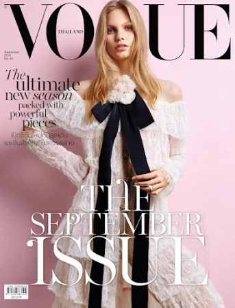 Model in off-white lace dress with black bow against pink background