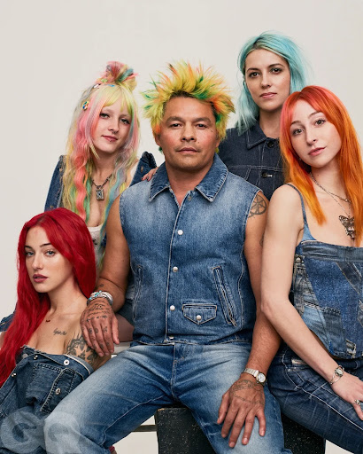 Group portrait of five people with brightly colored hair in denim clothing, posed in front of a white backdrop. Casual style.