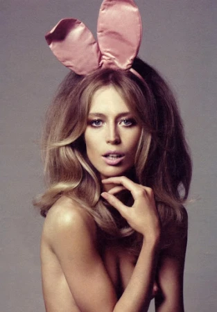 Glamour headshot of woman with blonde hair wearing pink bunny ears and bare shoulders in a studio, eye-level angle.