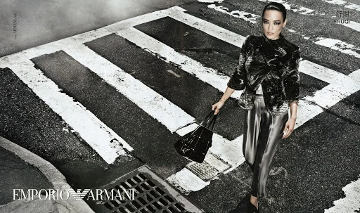 Woman in patterned jacket and satin trousers holding handbag on a pedestrian crosswalk