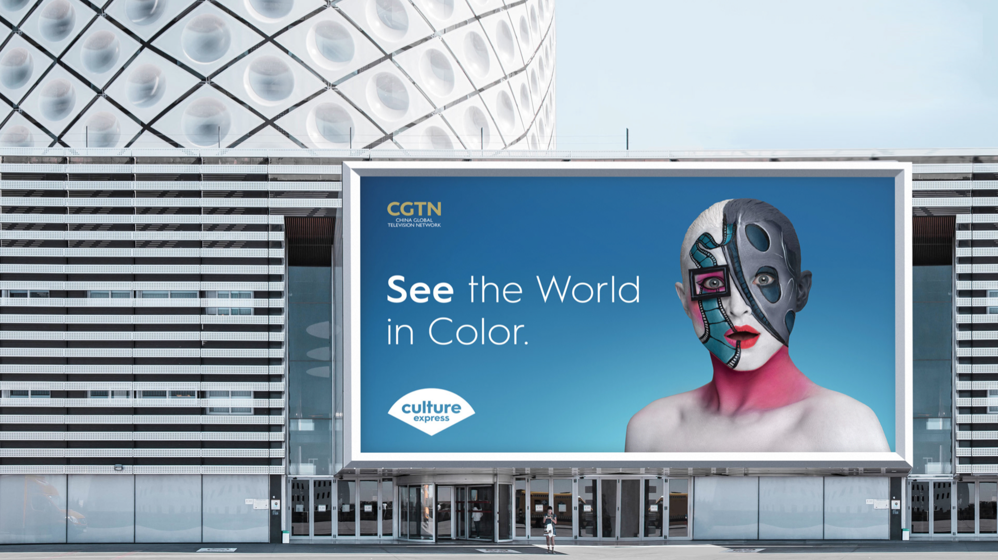 Outdoor billboard advertises CGTN's Culture Express with a person's digitally altered face, set against an architectural facade.