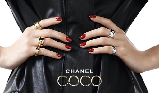 Close-up shot featuring a fair-skinned adult female model showcasing an array of gold and silver rings, set against a backdrop of a black leather garment.