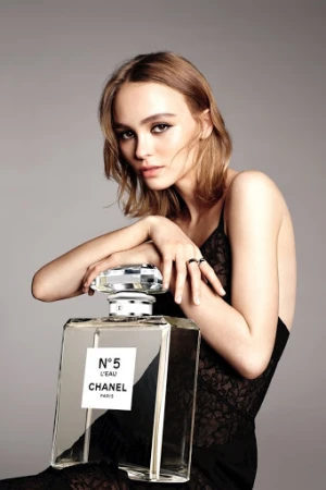 Elegant woman posing with Chanel No. 5 L'Eau perfume bottle in a beauty advertisement, showcasing classic style and sophistication.