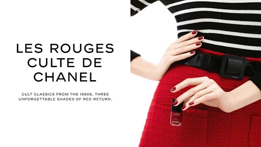 Chanel advert featuring woman's torso in red skirt and striped top with red manicure, holding nail polish bottle; text overlay.