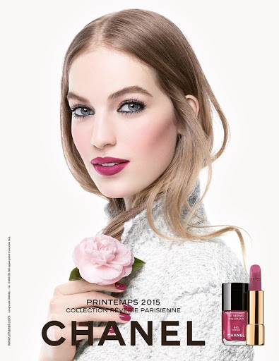 Cosmetics ad featuring a light-skinned woman with pink lipstick, holding a pink flower, and a bottle of nail polish by Chanel.