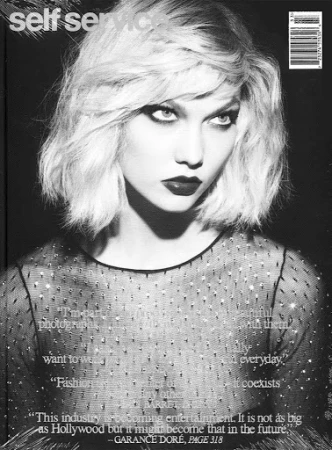 Monochrome magazine cover portrait of a blonde woman wearing a dark sheer crystal-embellished top.