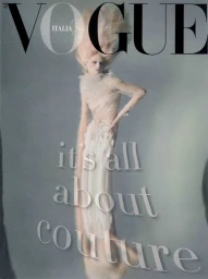 Magazine cover featuring a pale woman with flowing blonde hair wearing a sheer white couture gown against a grey background.
