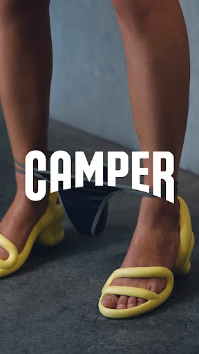 This is a vertically-oriented fashion shot featuring the legs of a human wearing yellow sandals, with black underwear suspended between their legs.