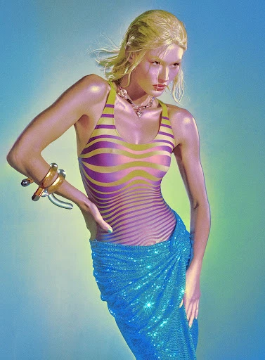 A slender woman poses in a shimmering blue sarong and wavy-patterned bodysuit against a blended blue and green backdrop.
