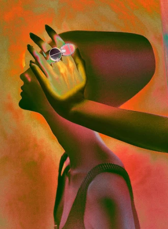 Conceptual portrait of a person with a large ring covering the eye, against an orange-toned background with soft, diffused lighting.