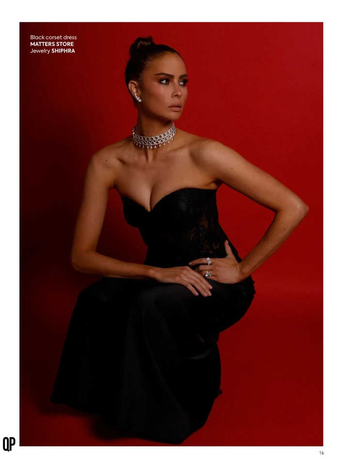 Woman in a black strapless corset dress and diamond jewelry posing against a solid red backdrop by photographer Shotarry