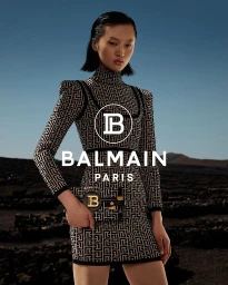 Asian woman wearing patterned monogram dress holding matching handbag against volcanic landscape