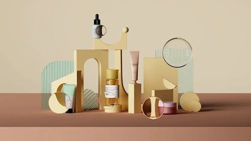 Product photography of assorted skin care products arranged on geometric yellow and brown platforms against a beige backdrop. 