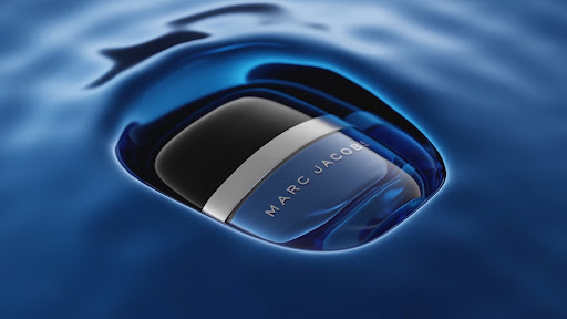 Blue Marc Jacobs perfume bottle submerged in deep blue rippling water creating concentric circles