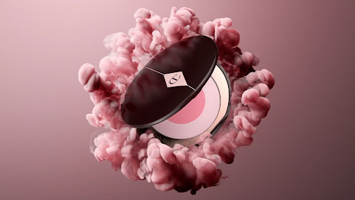 Cosmetic powder product shot with pink powder and brown packaging surrounded by pink cloud-like forms on a gradient backdrop.