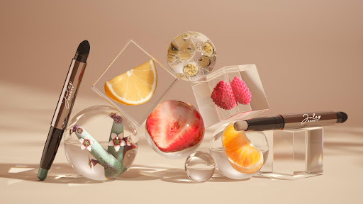 Beauty product still life with fruit in glass spheres and clear cubes against a soft beige backdrop in studio lighting.