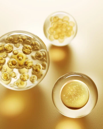 Close-up of three clear spheres containing golden particles on a gold surface, showcasing abstract beauty and scientific visualization.