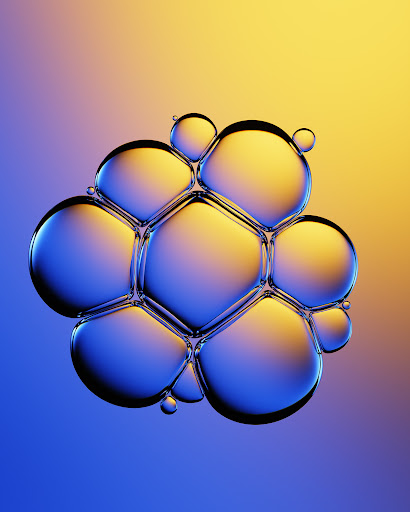 Macro shot of interconnected soap bubbles shimmering with blue and yellow iridescence against a soft gradient background.