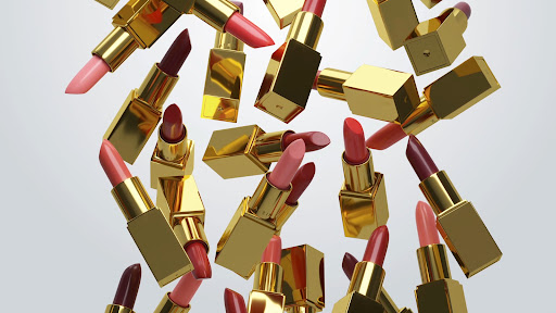 Floating collection of gold tube lipsticks in various shades of pink and red against a soft gradient gray background. Makeup concept.