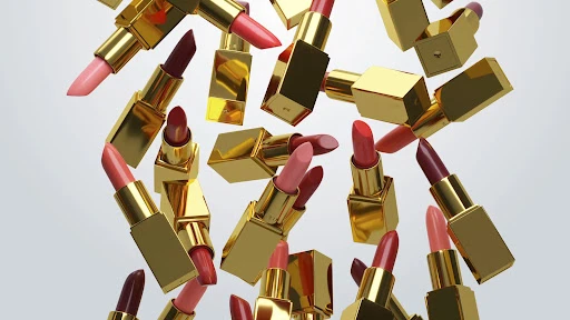 Floating collection of gold tube lipsticks in various shades of pink and red against a soft gradient gray background. Makeup concept.