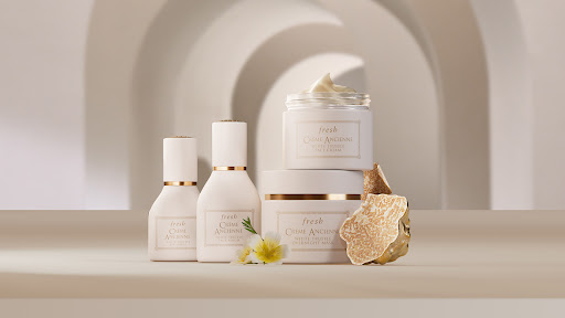 Still life of Fresh Crème Ancienne skincare products against a cream-colored background with arched architectural details and flowers.