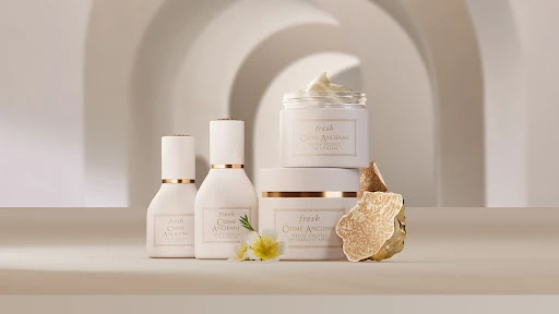 Still life of Fresh Crème Ancienne skincare products against a cream-colored background with arched architectural details and flowers.