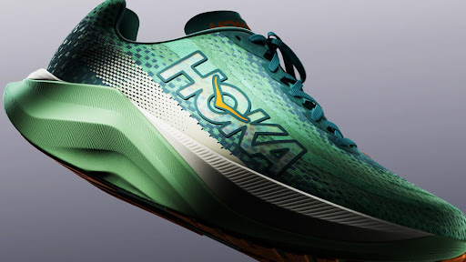 Close-up studio shot of a green Hoka running shoe with teal laces and a white midsole against a grey gradient background.