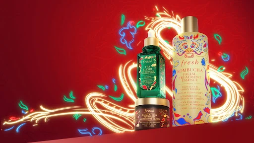 Fresh brand beauty product presentation on a red background with golden decorative swirls and floral accents. Three product sizes.