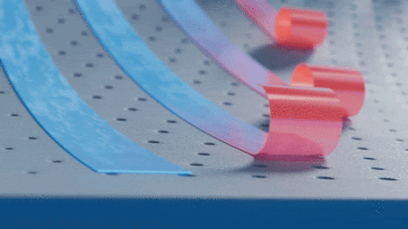 Close-up 3D render of curved blue and pink ribbons on a perforated metal surface under soft studio lighting.