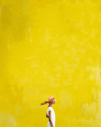 Model in white top wearing a colourful headscarf against a vibrant yellow background