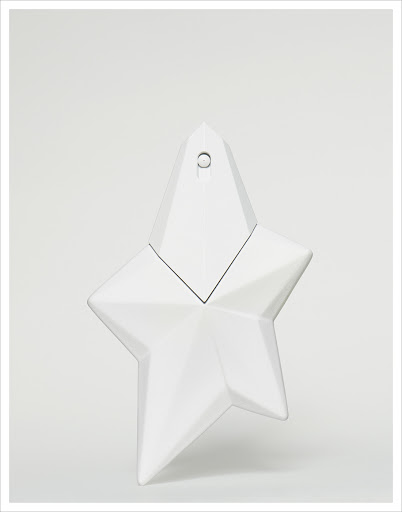 Elegant close-up studio shot of a glossy, star-shaped perfume bottle in pristine white against a light background, showcasing its unique design.